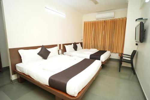 two beds in a hotel room with a television at HOTEL ABHISHEK, Shirdi in Shirdi
