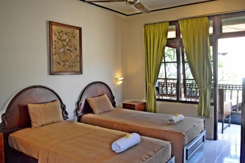 a bedroom with two beds and a balcony at Yulia 2 Homestay Sanur in Sanur