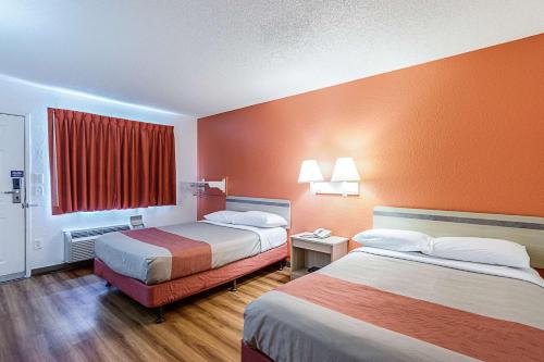 a hotel room with two beds with orange walls at Motel 6 Modesto, CA in Modesto
