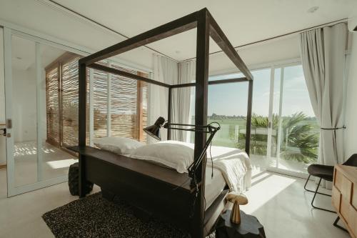 a bedroom with a canopy bed and a large window at The Iggy Villa 2BR in Cemagi