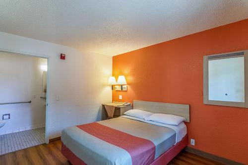 a hotel room with a bed with an orange wall at Motel 6 Modesto, CA in Modesto