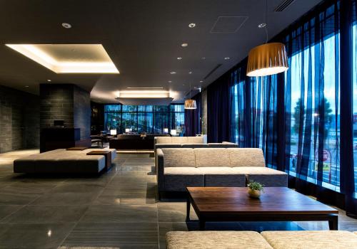a living room with couches and a table and windows at Daiwa Roynet Hotel Nagoya Taiko dori Side in Nagoya