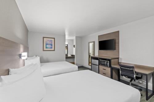 a hotel room with two beds and a desk and a television at Americas Best Value Inn Austin in Austin