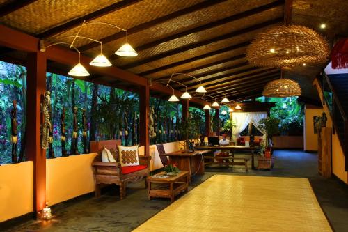 a lobby of a resort with tables and chairs and windows at Jungle Retreat by Kupu Kupu Barong in Ubud