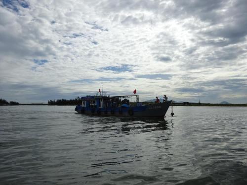 a blue boat on the water under a cloudy sky at Cham Island Smiles Homestay in Tân Hiệp