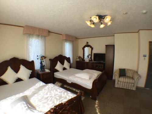 una camera con due letti e una sedia di Petit Hotel Corinthian a Rebun