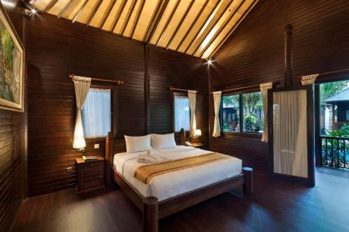 una camera da letto con un letto, pareti e finestre in legno di Coconut Boutique Resort a Senggigi