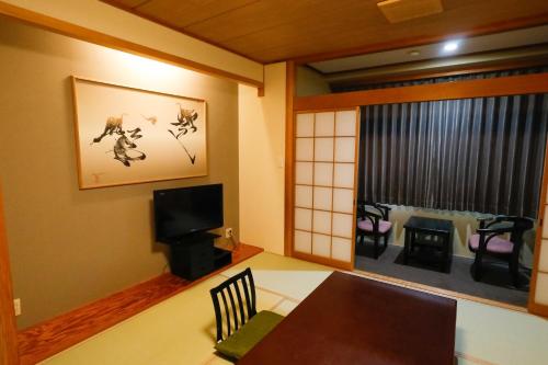 a dining room with a table and a tv and a window at Fuji Yamanakako Hotel in Yamanakako