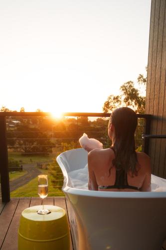a woman sitting in a bath tub with the sunset at Architecturally Designed Rural Retreat 3 bedroom HOUSE or 1 bedroom CABIN with more than 150 five stars rating in Forcett