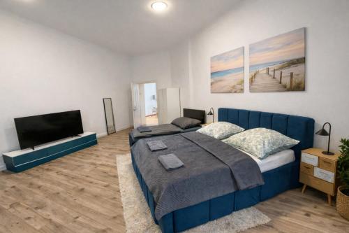 a bedroom with a blue bed and a flat screen tv at City Rooms Koblenz Hbf in Koblenz