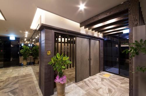 a lobby with a large wooden door and a plant at Jinju Kai Hotel in Jinju