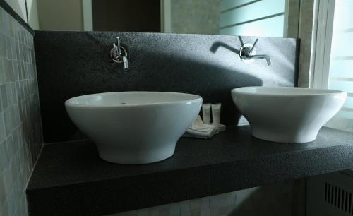 a bathroom with two white sinks on a counter at Hotel Acacia in Bruges