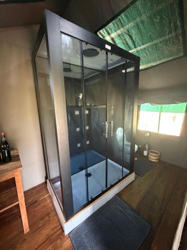 a glass shower in a room with a wooden floor at Tangi Elephant Camp in Pakwach East