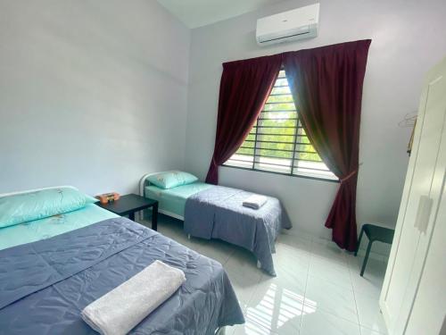 a room with two beds and a window with a window at Homestay Babah in Jitra