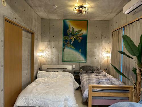 a bedroom with two beds and a painting on the wall at オランウータンApple House Ginowan in Ginowan