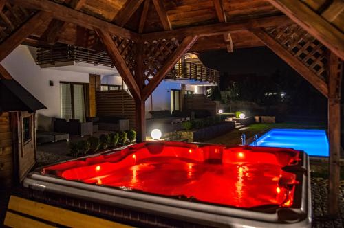 a red bath tub in a backyard at night at Apartamenty Pod Łysicą & SPA - przy stoku, basen, jacuzzi, sauna in Krajno Pierwsze