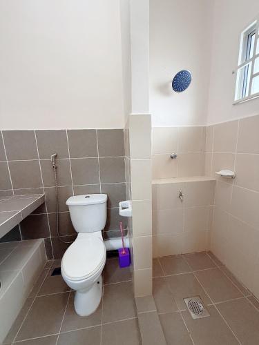 a bathroom with a white toilet and a shower at EQAMEL Homestay 2 in Sandakan