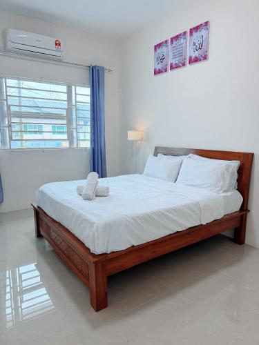 a bedroom with a large bed with white sheets at EQAMEL Homestay 2 in Sandakan