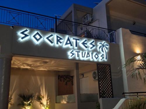 a lit up sign on the side of a building at Socrates Studios and Suites in Tigaki