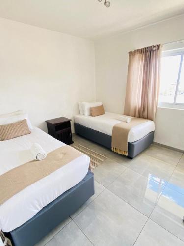 ein Hotelzimmer mit zwei Betten und einem Fenster in der Unterkunft City Duplex Trift Towers Apartment in Windhoek