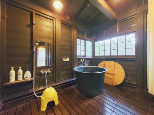 a bathroom with a tub and a wooden floor at shoya yamaguchi in Koibuchi