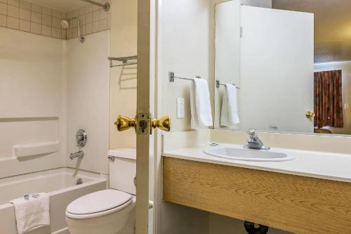 a bathroom with a toilet and a sink and a tub at Rodeway Inn Magic Mountain Area in Castaic