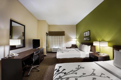 a hotel room with two beds and a desk at Sleep Inn & Suites Valdosta Mall Area in Valdosta