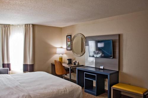 a hotel room with a bed and a desk and a mirror at Comfort Inn & Suites Geneva- West Chicago in Geneva