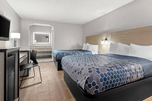 a hotel room with two beds and a desk at Rodeway Inn North Charleston - Ashley Phosphate in Charleston