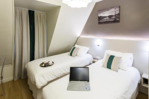 a hotel room with two beds with a laptop on them at Modern Hotel in Paris