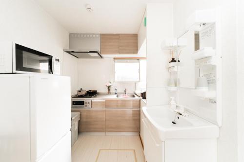 a white kitchen with a sink and a refrigerator at New Super Deals Now Available Direct Access to Akihabara Shinjuku and Disneyland in Tokyo