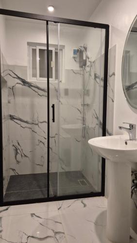 a bathroom with a glass shower and a sink at Edades Farms in Taysan