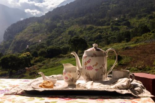 a tea set on a table with a view of a mountain at Hullathy by Red Earth in Ooty