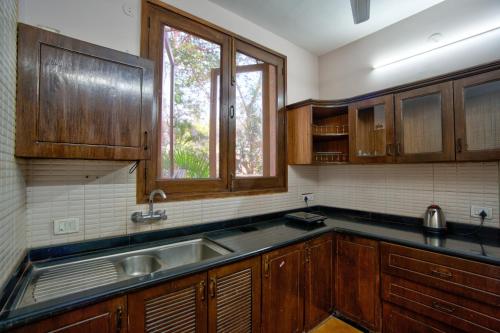 a kitchen with wooden cabinets and a sink at Aveeno Resort with Swimming Pool and Jacuzzi Near Calangute and Baga in Sangolda