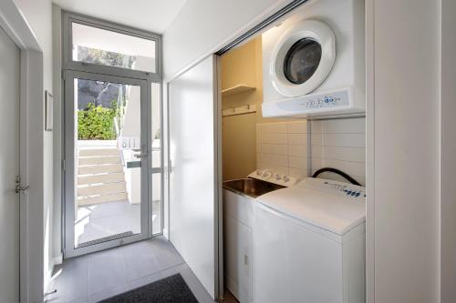 a small white kitchen with a washer and dryer at Swiss-Belsuites Pounamu Queenstown in Queenstown