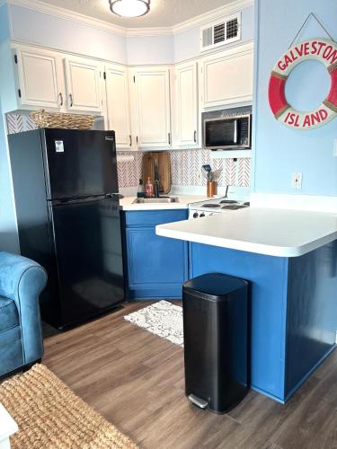a kitchen with a black refrigerator and white cabinets at Boltons Bungalow Casa Del Mar in Galveston
