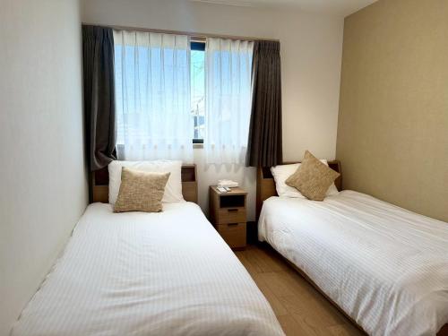 two beds in a small room with a window at Akikawa Toshima 2 プレミアム鉄骨 一棟貸切ヴィラ in Kumamoto