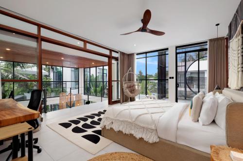 a bedroom with a large bed and a desk and windows at Baliwood Residence Villas by BREIG in Munggu