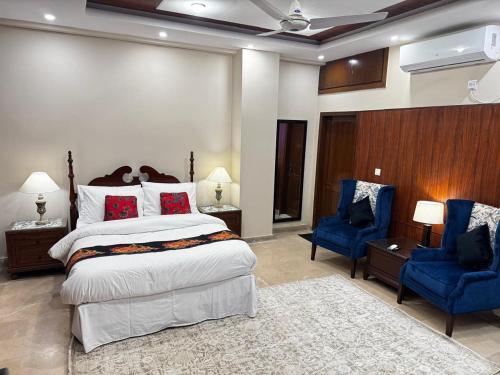 a bedroom with a large bed and two blue chairs at Pent House Executive Resedency in Dargai
