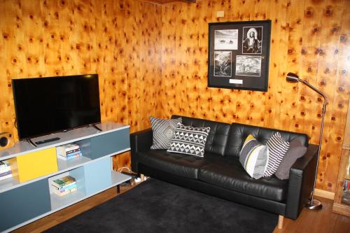 a living room with a black leather couch and a television at La Moussiere in Morgins