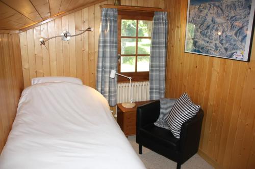 a bedroom with a bed and a chair and a window at La Moussiere in Morgins