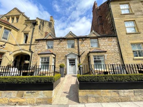 an old stone house with a black fence at The Bondgate Boutique in Alnwick