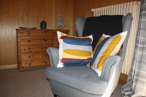 a blue chair with pillows on it next to a dresser at La Moussiere in Morgins