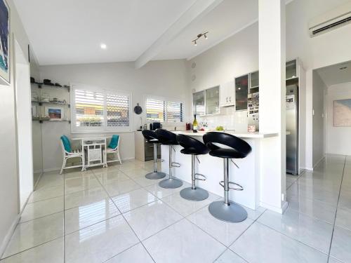a kitchen with stools and a counter in a room at Coastal retreat, private, wine, netflix by Custom Bnb Hosting in Buddina