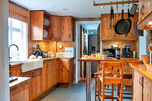 a kitchen with wooden cabinets and a counter top at Cricketers cottage in Tirley