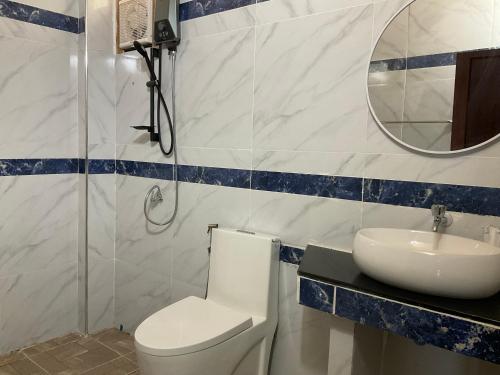 a bathroom with a toilet and a sink and a mirror at Pan guest house Donkhone in Ban Donsôm