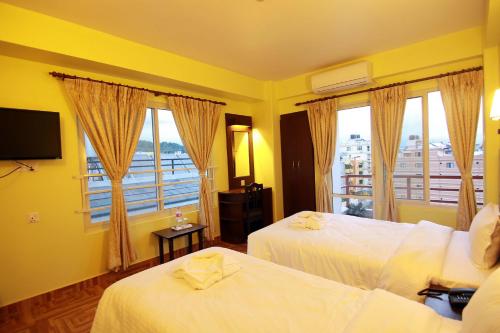 a hotel room with two beds and a balcony at My Hotel Pvt Ltd in Pokhara
