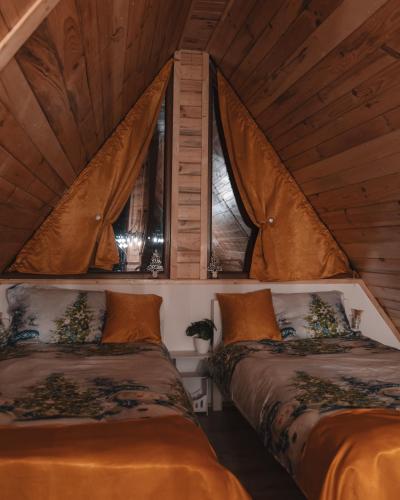 two beds in a room with two windows at La Poalele Vulcanilor in Densuş