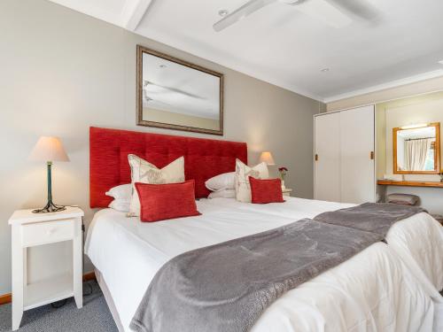 a bedroom with a large bed with a red headboard at Pumula Lodge 4 Star Guesthouse Knysna in Knysna