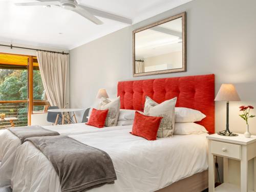 a bedroom with two beds and a red headboard at Pumula Lodge 4 Star Guesthouse Knysna in Knysna